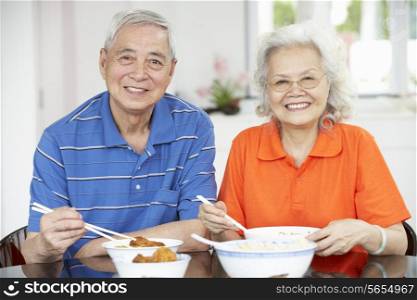 Senior Chinese Couple Sitting At Home Eating Meal