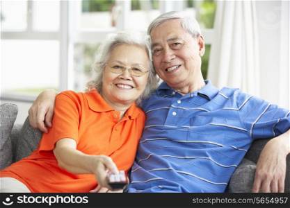 Senior Chinese Couple Watching TV On Sofa At Home