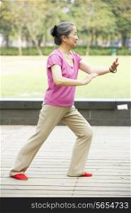 Senior Chinese Woman Doing Tai Chi In Park