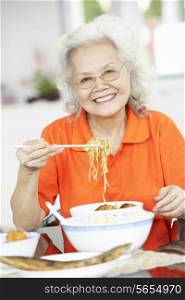 Senior Chinese Woman Sitting At Home Eating Meal