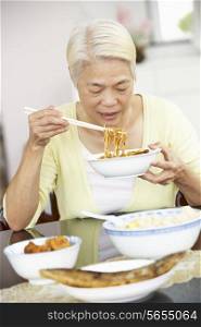 Senior Chinese Woman Sitting At Home Eating Meal
