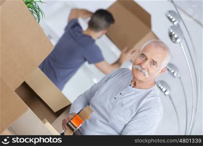 senior closing a cardboard box as he is moving houses