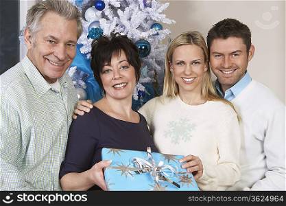 Senior couple and mid adult couple in front of Christmas tree, portrait