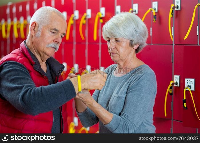 senior couple attaching locker key around wrist