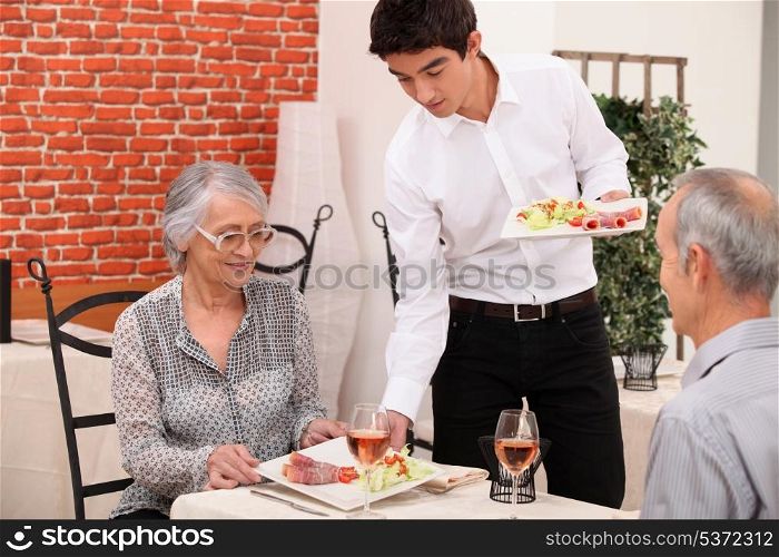 Senior couple being served food in a restaurant