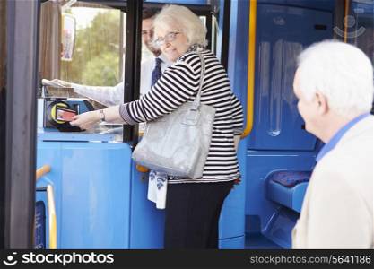 Senior Couple Boarding Bus And Using Pass