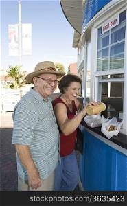 Senior couple buying hot dogs at food stand