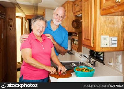 Senior couple cooking together in the kitchen of their motor home.
