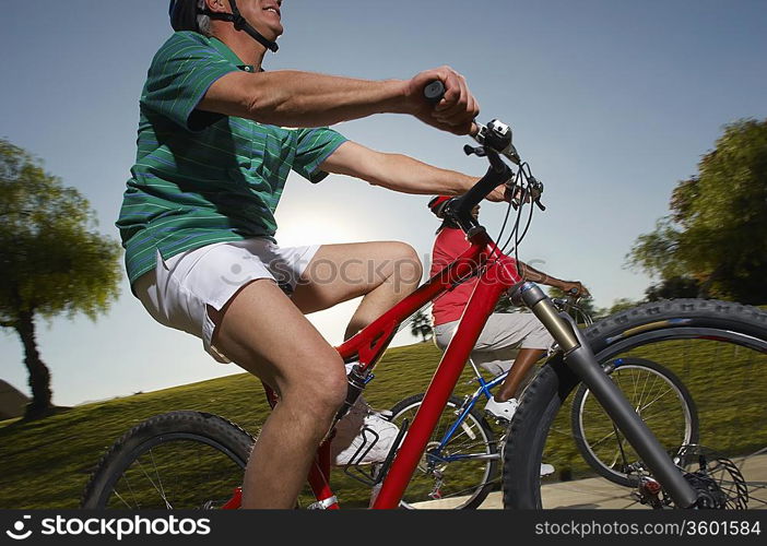 Senior couple cycling in park at dusk