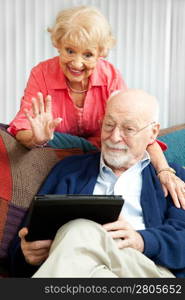 Senior couple doing a video chat with their grandchildren using their tablet PC.