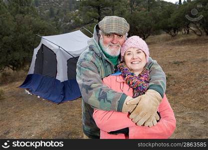 Senior couple embracing in front of tent, portrait