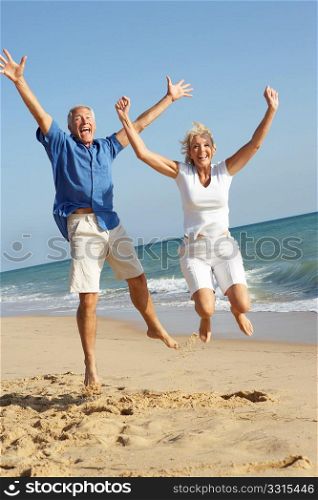 Senior Couple Enjoying Beach Holiday Jumping In Air
