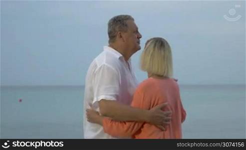 Senior couple enjoying slow dance at the seaside in the evening. Mature love and romantic relationships
