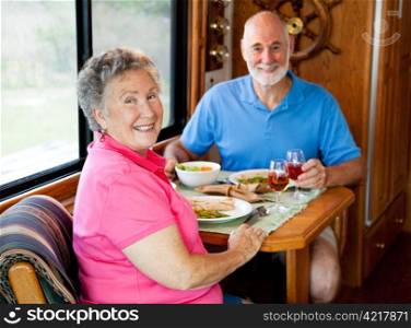 Senior couple enjoys a healthy lunch in the kitchen of their motor home. Focus on the wife.