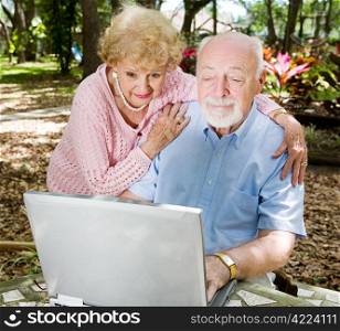 Senior couple enjoys using their computer outdoors.