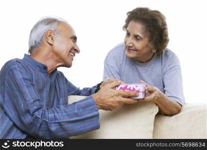 Senior couple exchanging gifts over white background