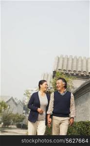 Senior couple going for a stroll in Beijing by traditional building, holding hands
