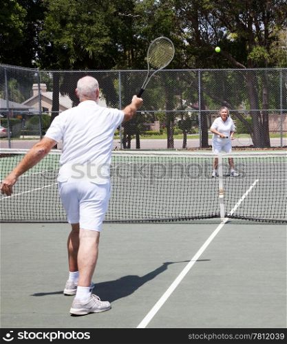 Senior couple having a game on the tennis court.