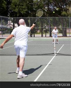 Senior couple having a game on the tennis court.