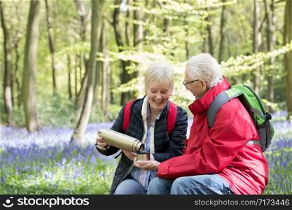 Senior Couple Having Drink From Flask On Walk Through Bluebell Wood