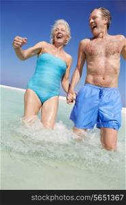 Senior Couple Having Fun In Sea On Beach Holiday