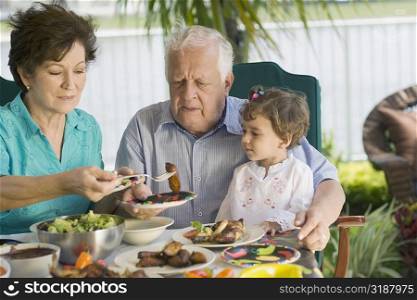 Senior couple having lunch with their granddaughter