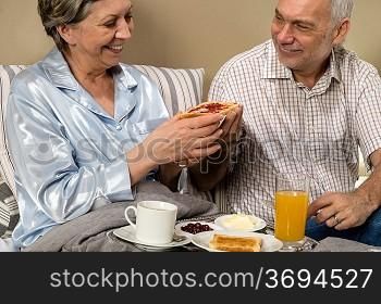 Senior couple having romantic morning breakfast in bed