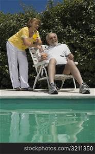Senior couple holding glasses of juice at the poolside