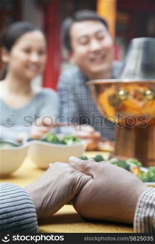 Senior couple holding hands at a family meal