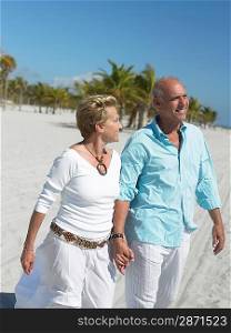 Senior couple holding hands on tropical beach