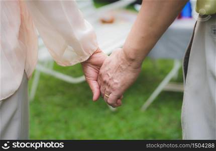 Senior couple holding hands together in garden at home
