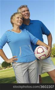 Senior couple holding soccer ball in park