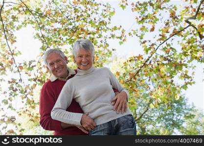 Senior couple hugging near trees