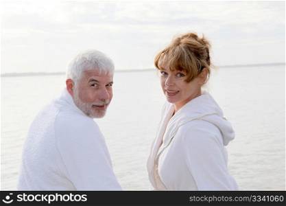 Senior couple in bathrobe sitting on a pontoon