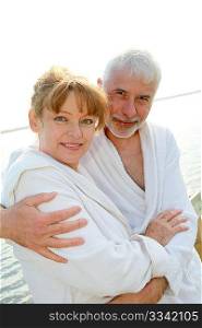 Senior couple in bathrobe standing on a pontoon