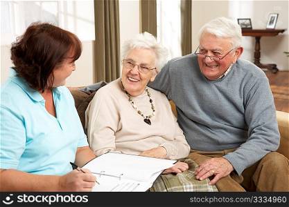 Senior Couple In Discussion With Health Visitor At Home