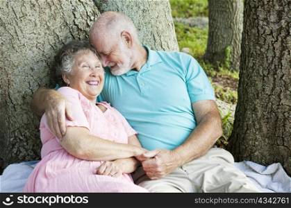 Senior couple in love. He&rsquo;s whispering something funny in her ear.