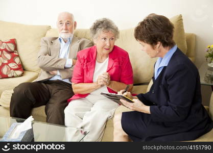 Senior couple in marriage counseling. The wife talks while the counselor takes notes.