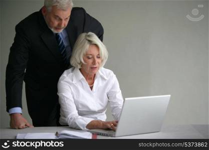 Senior couple in suit in front of a laptop computer