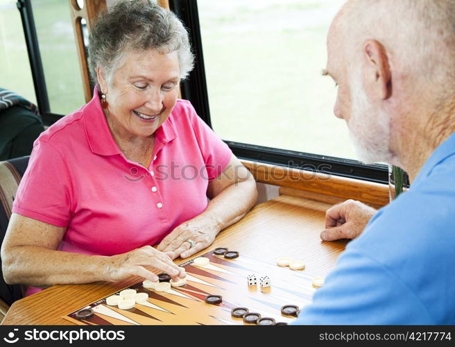 Senior couple in the kitchen of their motor home playing backgammon.