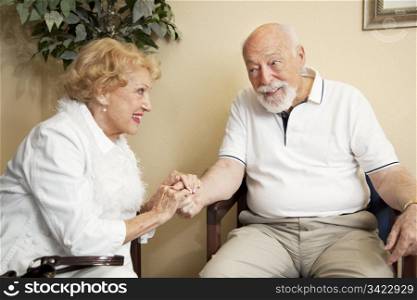 Senior couple in the waiting room of the doctor&rsquo;s office holding hands for moral support.