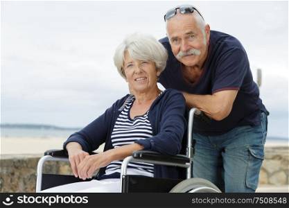 senior couple in wheelchair by the sea
