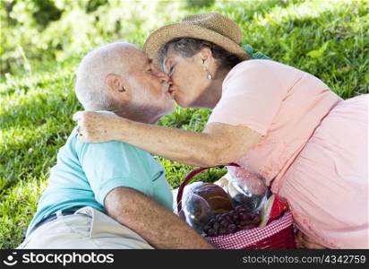 Senior couple kissing on a romantic picnic in the park.