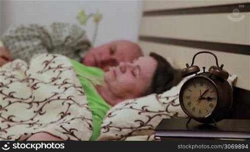 Senior couple laying in bed and peacefully sleeping. Focus on watch.