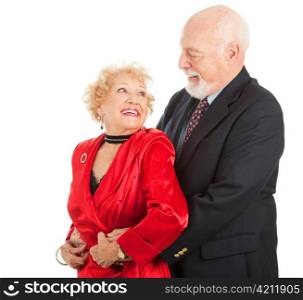 Senior couple look lovingly into each others eyes as they dance. Isolated on white.