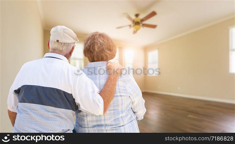 Senior Couple Looking Into Empty Room of House.