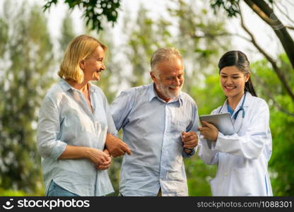 Senior couple man and woman talking to young nurse or caregiver in the park. Mature people healthcare and medical staff service concept.