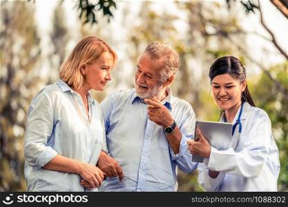 Senior couple man and woman talking to young nurse or caregiver in the park. Mature people healthcare and medical staff service concept.