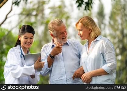 Senior couple man and woman talking to young nurse or caregiver in the park. Mature people healthcare and medical staff service concept.