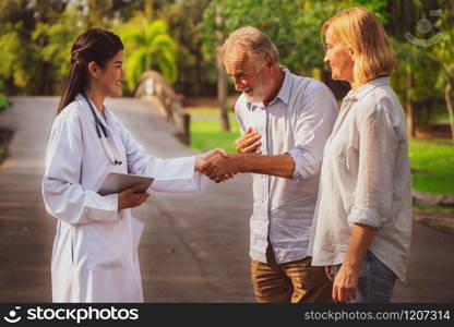 Senior couple man and woman talking to young nurse or caregiver in the park. Mature people healthcare and medical staff service concept.. Senior couple talking to nurse or caregiver.